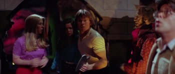 Movie still from “The Funhouse” (1981), directed by Tobe Hooper – A man holding an object while standing next to a woman; Medium shot, Low angle