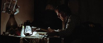 Movie still from “The Funhouse” (1981), directed by Tobe Hooper – A man sitting on a bed looking at a laptop; Medium shot, Low angle