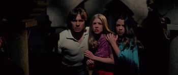 Movie still from “The Funhouse” (1981), directed by Tobe Hooper – A group of people standing next to each other in a room; Medium shot, Low angle