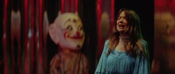 Movie still from “The Funhouse” (1981), directed by Tobe Hooper – A woman standing in front of a creepy clown statue; Medium shot, Over the shoulder angle