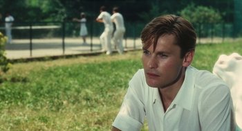 Movie still from “The Garden of the Finzi-Continis” (1970), directed by Vittorio De Sica – A man sitting on the grass in front of a fence; Close Up shot, Low angle