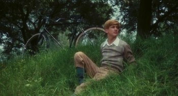 Movie still from “The Garden of the Finzi-Continis” (1970), directed by Vittorio De Sica – A man sitting in the grass next to a bicycle; Medium shot, Low angle