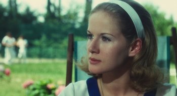 Movie still from “The Garden of the Finzi-Continis” (1970), directed by Vittorio De Sica – A woman with a headband sitting in a chair outside; Close Up shot, Over the shoulder angle