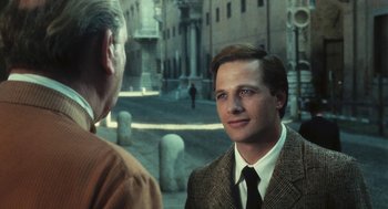 Movie still from “The Garden of the Finzi-Continis” (1970), directed by Vittorio De Sica – A man wearing a suit and tie standing next to another man; Close Up shot, Over the shoulder angle