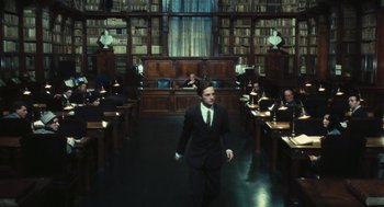 Movie still from “The Garden of the Finzi-Continis” (1970), directed by Vittorio De Sica – A man in a suit and tie in a library; Wide shot, Low angle