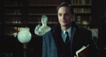 Movie still from “The Garden of the Finzi-Continis” (1970), directed by Vittorio De Sica – A man in a suit and tie holding a book in a library; Close Up shot, Over the shoulder angle