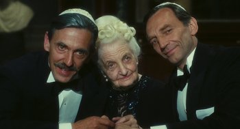 Movie still from “The Garden of the Finzi-Continis” (1970), directed by Vittorio De Sica – An older woman with two men in tuxedos posing for a picture; Close Up shot, High angle