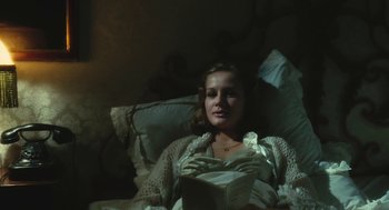 Movie still from “The Garden of the Finzi-Continis” (1970), directed by Vittorio De Sica – A woman laying in a bed reading a book; Medium shot, High angle