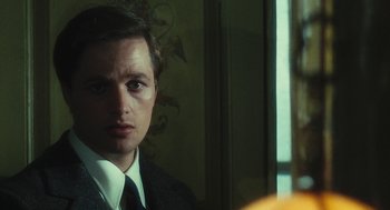 Movie still from “The Garden of the Finzi-Continis” (1970), directed by Vittorio De Sica – A man wearing a suit and tie in front of a mirror; Close Up shot, Over the shoulder angle
