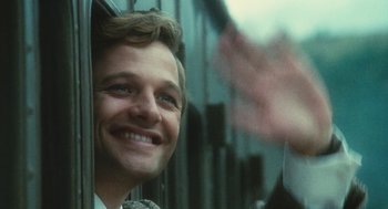 Movie still from “The Garden of the Finzi-Continis” (1970), directed by Vittorio De Sica – A man smiling while looking out of a train window; Close Up shot, Over the shoulder angle