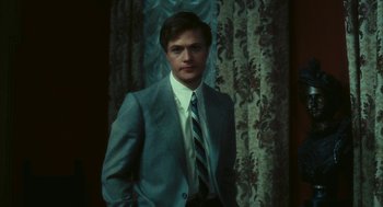 Movie still from “The Garden of the Finzi-Continis” (1970), directed by Vittorio De Sica – A man wearing a suit and tie standing in front of a curtain; Close Up shot, Low angle