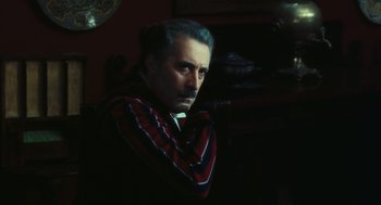 Movie still from “The Garden of the Finzi-Continis” (1970), directed by Vittorio De Sica – A man in a striped shirt is sitting in a chair; Close Up shot, Over the shoulder angle