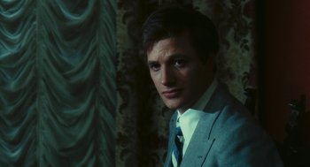 Movie still from “The Garden of the Finzi-Continis” (1970), directed by Vittorio De Sica – A man wearing a suit and tie in front of a curtain; Close Up shot, Over the shoulder angle
