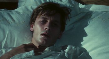 Movie still from “The Garden of the Finzi-Continis” (1970), directed by Vittorio De Sica – A man laying in a bed with his eyes closed; Close Up shot, High angle