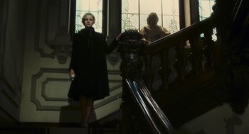 Movie still from “The Garden of the Finzi-Continis” (1970), directed by Vittorio De Sica – A woman standing on the stairs holding a cell phone; Wide shot, Low angle