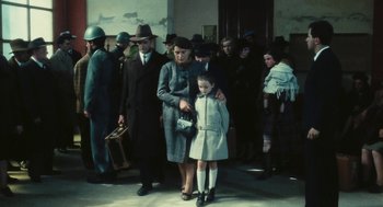 Movie still from “The Garden of the Finzi-Continis” (1970), directed by Vittorio De Sica – An older woman and a young girl are standing in front of a group of people; Wide shot, High angle