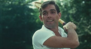 Movie still from “The Garden of the Finzi-Continis” (1970), directed by Vittorio De Sica – A man swinging a baseball bat on a field; Close Up shot, Over the shoulder angle