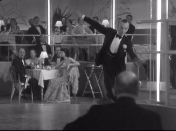 Movie still from “The Gay Divorcee” (1934), directed by Mark Sandrich – A man in a black suit is dancing in front of a crowd; Wide shot, High angle