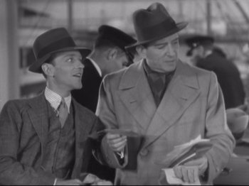 Movie still from “The Gay Divorcee” (1934), directed by Mark Sandrich – Two men in suits and hats are looking at papers; Medium shot, High angle
