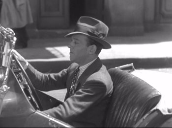 Movie still from “The Gay Divorcee” (1934), directed by Mark Sandrich – A black and white photo of a man driving a car; Medium shot, High angle