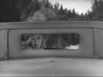 Movie still from “The Gay Divorcee” (1934), directed by Mark Sandrich – A reflection of a young girl in the rear view mirror of a car; Medium shot, High angle