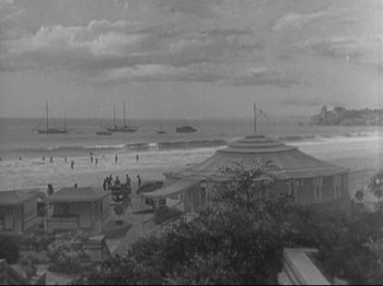 Movie still from “The Gay Divorcee” (1934), directed by Mark Sandrich – A black - and - white photo of a beach with boats in the water; Extreme Wide shot, High angle