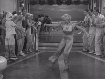 Movie still from “The Gay Divorcee” (1934), directed by Mark Sandrich – A woman dancing in front of a group of people; Wide shot, High angle