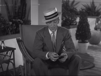 Movie still from “The Gay Divorcee” (1934), directed by Mark Sandrich – A black and white photo of a man in a suit and hat; Medium shot, High angle