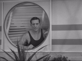 Movie still from “The Gay Divorcee” (1934), directed by Mark Sandrich – A black and white photo of a man in a tank top looking into a mirror; Medium shot, Low angle