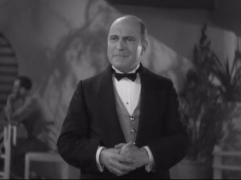 Movie still from “The Gay Divorcee” (1934), directed by Mark Sandrich – An old photo of a man in a suit and bow tie; Medium shot, Low angle