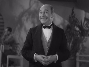 Movie still from “The Gay Divorcee” (1934), directed by Mark Sandrich – A man in a suit and bow tie smiling for the camera; Medium shot, Low angle