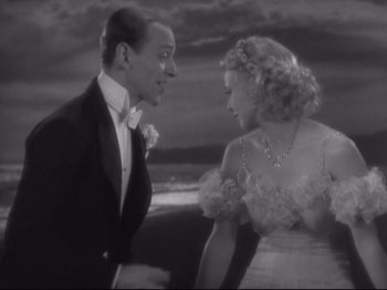 Movie still from “The Gay Divorcee” (1934), directed by Mark Sandrich – A man and a woman standing next to each other in front of the ocean; Medium shot, High angle