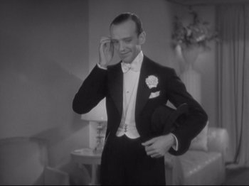 Movie still from “The Gay Divorcee” (1934), directed by Mark Sandrich – A man in a tuxedo adjusting his bow tie; Medium shot, Low angle