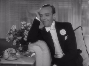 Movie still from “The Gay Divorcee” (1934), directed by Mark Sandrich – A man in a tuxedo sitting on a chair; Medium shot, High angle
