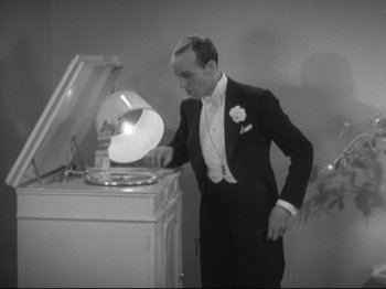Movie still from “The Gay Divorcee” (1934), directed by Mark Sandrich – A man standing next to an old record player; Medium shot, High angle