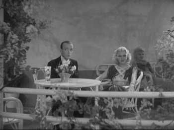 Movie still from “The Gay Divorcee” (1934), directed by Mark Sandrich – A black and white photo of a man and a woman sitting at a table; Wide shot, High angle