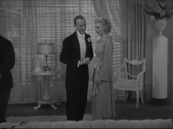 Movie still from “The Gay Divorcee” (1934), directed by Mark Sandrich – A man and a woman standing next to each other in a room; Wide shot, High angle