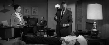 Movie still from “The Gazebo” (1959), directed by George Marshall – A man in a suit and tie standing in front of another man in a suit and tie; Medium shot, Over the shoulder angle