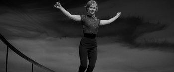 Movie still from “The Gazebo” (1959), directed by George Marshall – A black and white photo of a woman with her arms outstretched; Medium shot, Low angle