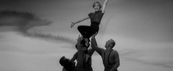 Movie still from “The Gazebo” (1959), directed by George Marshall – An old photo of a woman being lifted in the air; Medium shot, Low angle