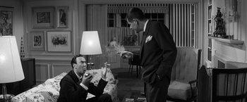 Movie still from “The Gazebo” (1959), directed by George Marshall – Two men in suits are in a living room; Medium shot, Low angle