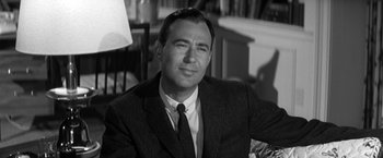 Movie still from “The Gazebo” (1959), directed by George Marshall – Black and white photograph of a man wearing a suit and tie; Close Up shot, Over the shoulder angle