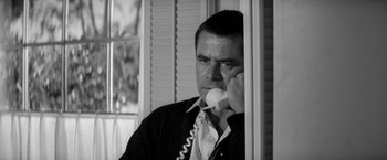 Movie still from “The Gazebo” (1959), directed by George Marshall – A black and white photo of a man talking on a phone; Close Up shot, Low angle