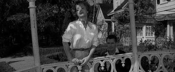 Movie still from “The Gazebo” (1959), directed by George Marshall – A woman standing next to a man on a fence; Medium shot, Low angle