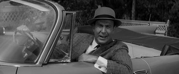 Movie still from “The Gazebo” (1959), directed by George Marshall – A black and white photo of a man in a suit and a hat; Close Up shot, Over the shoulder angle