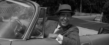 Movie still from “The Gazebo” (1959), directed by George Marshall – A black and white photo of a man in a suit and a hat; Close Up shot, Over the shoulder angle