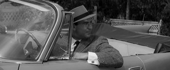 Movie still from “The Gazebo” (1959), directed by George Marshall – A black and white photo of a man in a suit and a hat; Medium shot, Over the shoulder angle