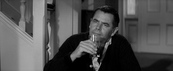 Movie still from “The Gazebo” (1959), directed by George Marshall – A black and white photo of a man drinking a glass of water; Close Up shot, Over the shoulder angle