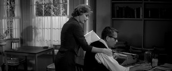 Movie still from “The Gazebo” (1959), directed by George Marshall – An old photo of a woman helping a man with a book; Medium shot, Over the shoulder angle