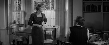 Movie still from “The Gazebo” (1959), directed by George Marshall – An old photo of a woman standing in front of a man; Medium shot, Over the shoulder angle